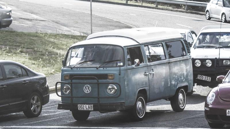 Close-up of a person's hands holding a portable power bank, plugging a USB-C cable into a modern smartphone. The background is a slightly blurred busy airport terminal.