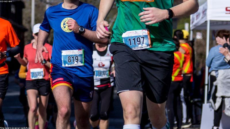 Active person jogging in a park wearing true wireless earbuds, clear sunny day