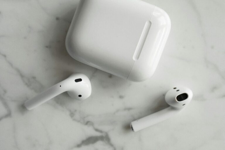 High-quality image of wireless earbuds and charging case on marble surface, showcasing modern technology.