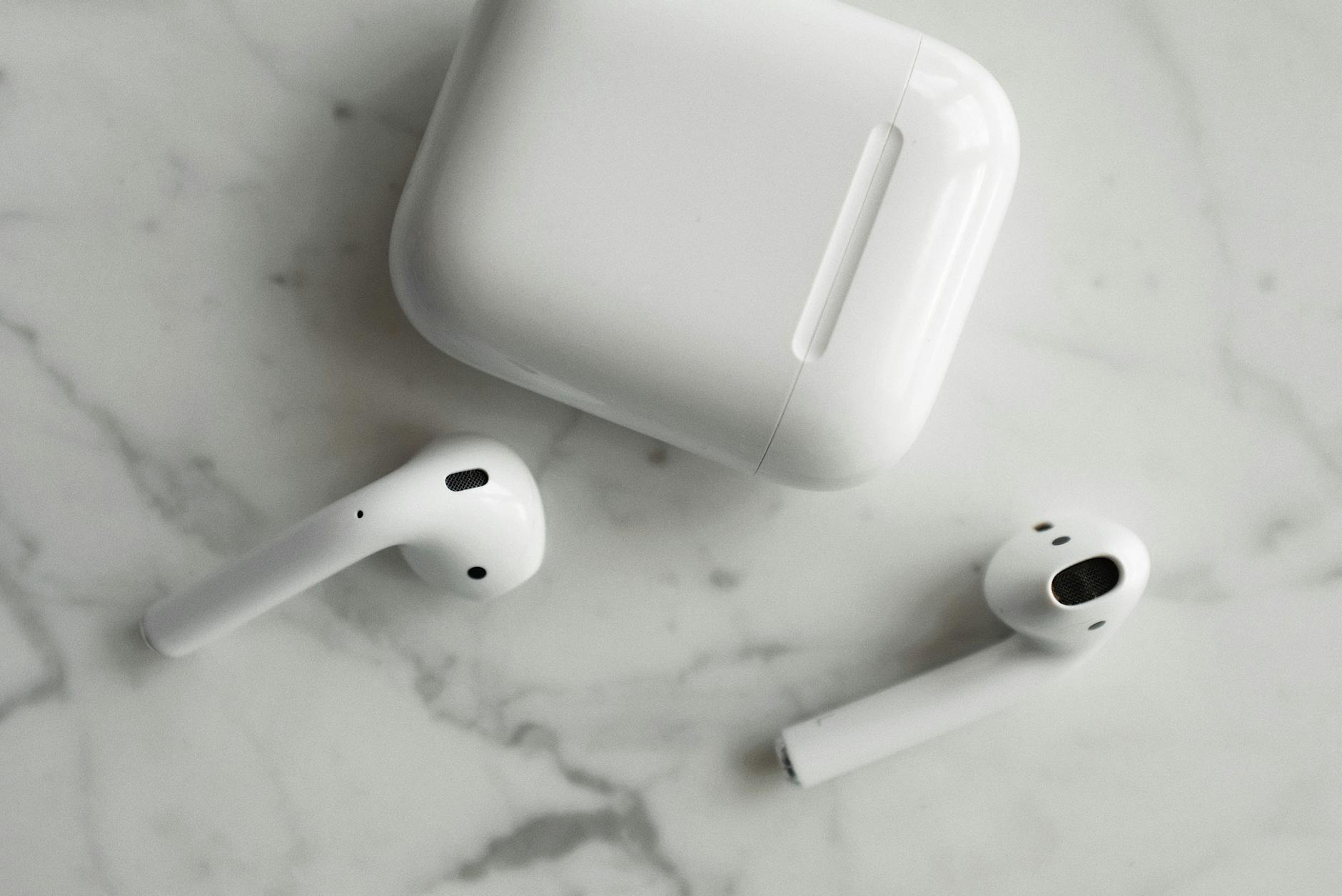 High-quality image of wireless earbuds and charging case on marble surface, showcasing modern technology.
