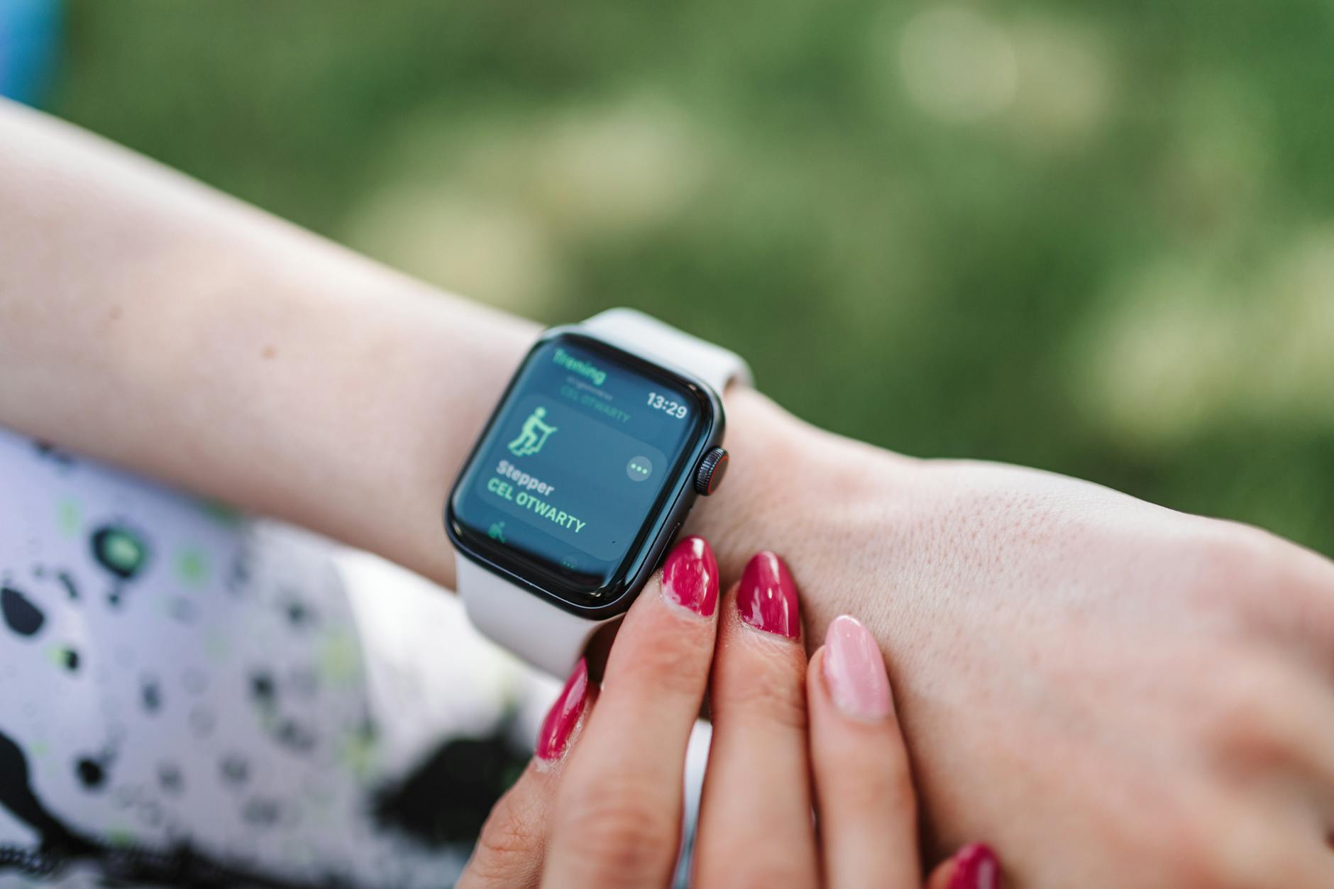 Woman interacting with a smartwatch outdoors displaying a fitness tracking app.