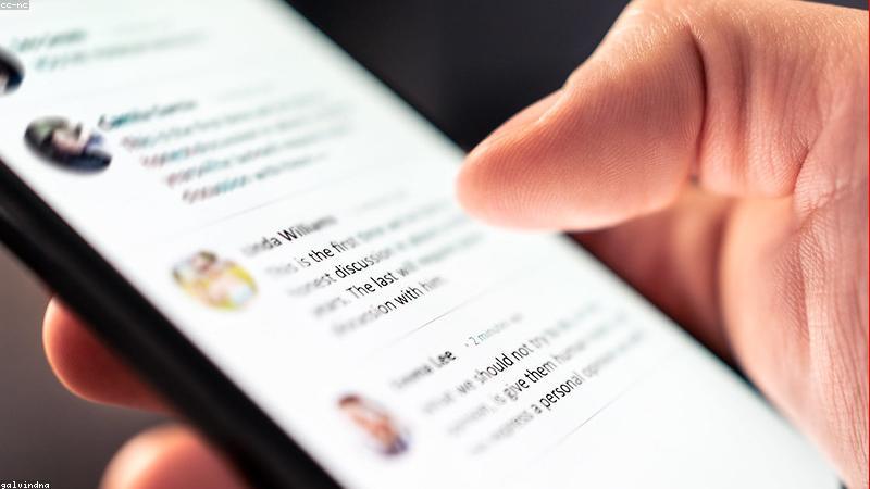 person using smartphone while commuting on a London train with a power bank connected