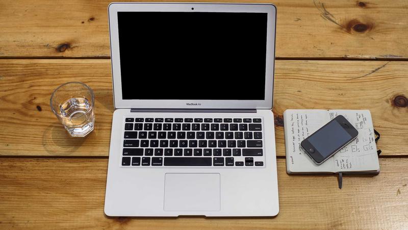 A stylized flat-lay image of a remote worker's tech stack: a laptop, noise-canceling headphones, a high-definition webcam, and a coffee cup, arranged neatly on a pastel background.